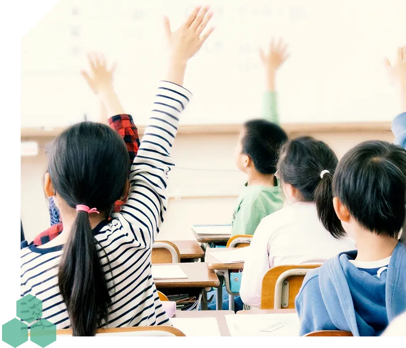 教室で手を挙げる子供たちの写真