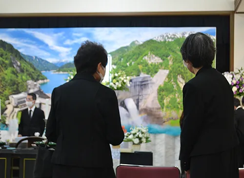 葬儀事例「父と息子の旅」のギャラリー画像2枚目 スクリーン祭壇をご覧になるご親族