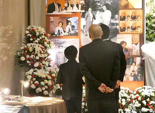 葬儀事例「赤の愛車と父との思い出」のギャラリー画像3枚目 メモリアルスクリーンをご覧になるご家族