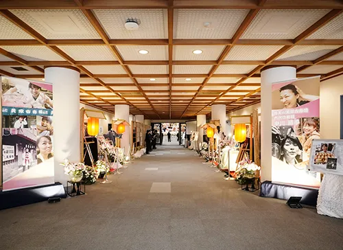 葬儀事例「5年間病気と闘い続けたママへ」のギャラリー画像3枚目 入り口から式場までたくさんのお写真が掲示