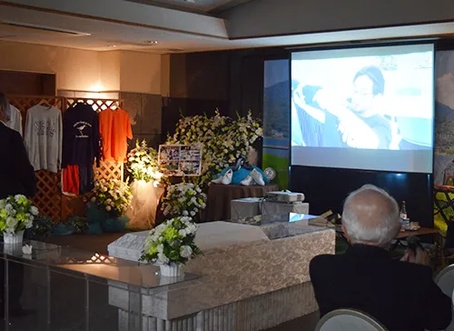 葬儀事例「ファッションデザイナーの父」のギャラリー画像3枚目 映像上映を見られる参列者